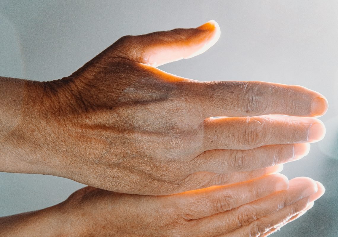 Hands held palms-up towards the sun, symbolizing the channeling of Reiki energy through the hands.